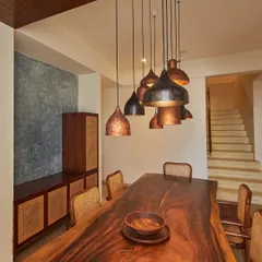 This dining space from the Magnolia Residence uses a live-edge wood table paired with cane chairs and custom pendant lights. The design creates a warm, inviting atmosphere that is both elegant and comfortable.