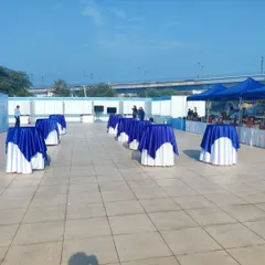 Cocktail tables draped in the client's brand colors, blue and white, are set up on the terrace. This arrangement provides space for networking and casual conversation during the corporate gathering.