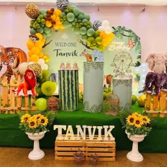 A 'Wild One' jungle theme with a touch of elegance. This setup features a green grass floor, sunflower arrangements, a wooden fence, and various animal props and cutouts.