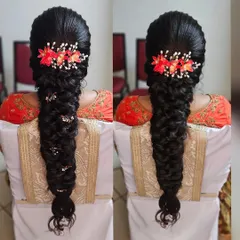 A beautiful fishtail braid, perfect for a muhurtham or reception. This hairstyle is adorned with delicate orange floral accessories, adding a pop of color and intricate detail.