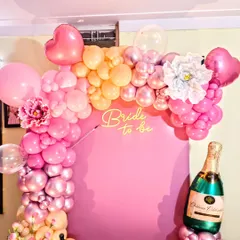 A close-up of the "Bride to be" neon sign and the ombre balloon garland. The mix of pink, peach, and metallic balloons creates a celebratory and picture-perfect backdrop for the bride.