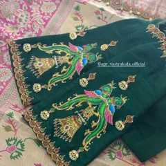 A rich green blouse with sleeves painted in a traditional style, depicting colorful peacocks and temple bells. The artwork is enhanced with kundan and zardosi details.