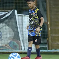 A young player practices his ball control, keeping the ball close while staying balanced. Mastering this skill is fundamental to becoming a confident footballer.