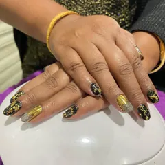 A luxurious combination of black, gold chrome, and silver glitter. The black nails have gold foil flakes embedded in them, creating a rich, textured look.