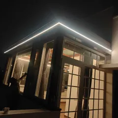 A dramatic night view of a glass pergola with integrated LED lighting. This structure transforms the outdoor space into a usable and striking feature of the home, even after dark.