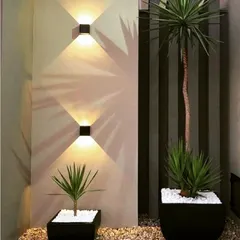 The right lighting can be a design element in itself. These modern up-and-down wall sconces cast dramatic, geometric shadows, adding architectural interest to this minimalist corner arrangement.