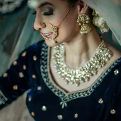 A traditional bridal look with a touch of modern elegance. The focus is on her kundan jewelry, nath, and the soft glam makeup that enhances her features.