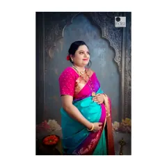 A serene portrait of an expecting mother cradling her belly. The traditional saree and the classic studio backdrop with arch details add a touch of timeless elegance to this special moment.