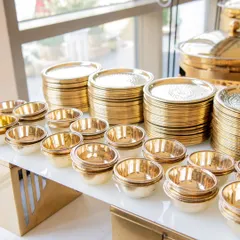 Stacks of shining, gold-toned plates and bowls, ready for guests. I ensure that even the basic elements of the dining experience reflect a standard of luxury and attention to detail.