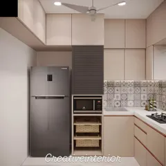 Even in a compact space, a fully functional modular kitchen is possible. This design cleverly integrates the refrigerator, microwave, and storage baskets, using light-colored laminates and patterned tiles to make the area feel open and bright.