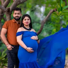 A beautiful outdoor couple portrait. The mom to be looks stunning in her blue gown, and her partner stands proudly by her side, creating a lovely family picture.