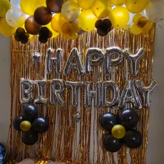 This is another shimmer curtain backdrop, this time with silver "Happy Birthday" foil letters. The balloon garland uses a mix of gold, brown, and black balloons for a stylish and modern look.