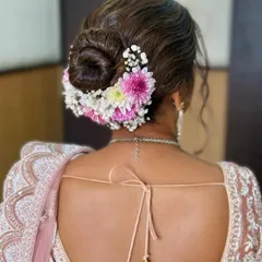 A beautiful bridal bun featuring a mix of baby's breath and pink chrysanthemums. This style is soft, romantic, and perfect for a day wedding.