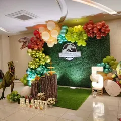 An alternate view of the dinosaur party setup, showing the complete balloon arch and prop arrangement.