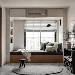 This versatile space serves as both a living area and a guest room. The cozy daybed with black plaid upholstery is set against a white brick wall with built-in book niches, creating a perfect reading nook that is both stylish and functional.