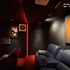 The interior of the home theater, showing the plush recliners and custom wall art. The dark color scheme minimizes light reflection, enhancing the viewing experience.