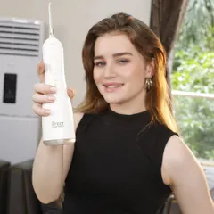 A model presents a white water flosser, showcasing its clean design. This type of shot, featuring a model interacting with the product, is highly effective for e-commerce and social media.