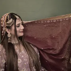 A playful moment with the dupatta. This shot gives a better view of her side-parted hairstyle and the elegant placement of her headpiece.
