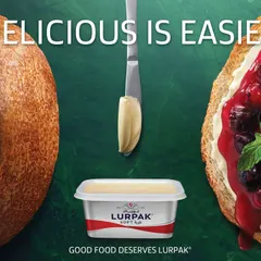 This image from the Lurpak campaign focuses on a classic combination: fresh sourdough bread with butter and jam. The lighting is designed to emphasize the crusty texture of the bread and the glossy richness of the fruit jam.