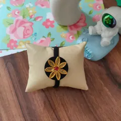 This hairband features a beautiful golden flower motif created with gotapatti work. It's a simple and elegant hair accessory.