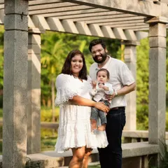 This wider shot from the same outdoor family session frames the family beautifully under a stone pergola. Using architectural elements adds structure and depth to outdoor portraits, creating a more formally composed yet still natural family photograph.