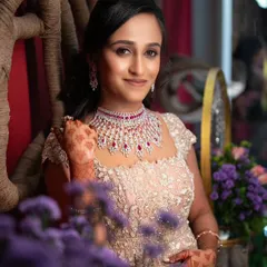 A vision in a beige and ruby-studded gown. This reception look is pure glamour, with soft, smoky eyes, a defined lip, and a romantic half-up hairstyle, all framed by beautiful floral decor.