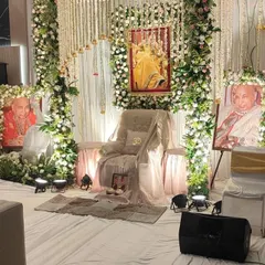 An elegant and pure white theme for a Guru Ji darbar. The gaddi is decorated with soft white fabric, surrounded by pillars and arches of white and cream flowers, creating a peaceful and divine atmosphere.