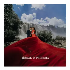 A stunning wide shot of a couple standing before a massive waterfall, with the bride's red dress spread out dramatically. This image showcases our ability to create epic, fairytale-like moments in nature.