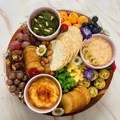 I call this one 'Flowers & Fromage'. A beautiful wooden platter filled with my signature dips, cheese balls, crackers, nuts, and fresh fruit, all decorated with edible flowers for an extra touch of elegance.