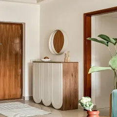 A chic and contemporary foyer console. This piece features a unique design with rounded, fluted doors in a two-tone wood and white finish, creating a soft and modern look.