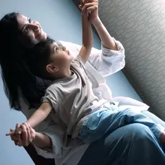 A mother and son share a happy moment, looking up towards the light. This image captures the pure connection and joy found in everyday interactions.