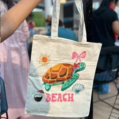 A close-up of a beautifully painted tote bag with a beachy turtle design. This is a perfect example of how you can carry your creativity wherever you go.