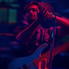 The bassist feeling the groove under the vibrant stage lights. Our performances are a visual and auditory treat, perfect for high-end events.