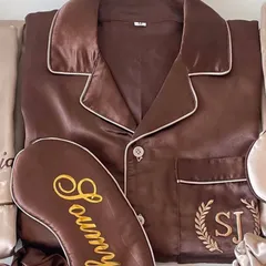 A detailed look at our personalised satin night suit for the bride or bridesmaid. This rich brown set features custom embroidery with initials in a laurel wreath and a matching sleep mask with the name 'Soumya'.