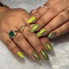 This stunning cat-eye effect in a vibrant chartreuse green is a client favorite. The magnetic polish creates a shifting, multi-dimensional look that catches the light beautifully, complemented here by elegant gold rings.