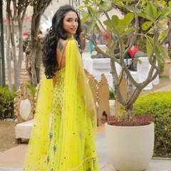 A full-length shot of the bride, showcasing her stunning yellow outfit and the joyful, glowing makeup look.