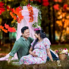 An outdoor picnic setup provides a relaxed and romantic setting for a couples maternity shoot. This couple's connection shines through as they sit together, surrounded by colorful props and autumn leaves.