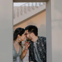 A sweet, stolen moment framed by a window, capturing the intimacy and romance of the couple.