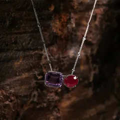 Here, the dark, rugged texture of the wood highlights the intricate details and contrasting colors of the amethyst and ruby stones in this necklace.