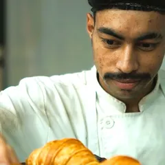 One of our talented bakers, focused on arranging fresh croissants. Our team's attention to detail and passion for their craft is what makes our food special.