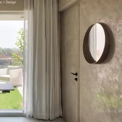 A detail from the Agra Fort Project bedroom, showing the textured lime plaster wall and a simple, elegant mirror. The door leads out to the terrace, reinforcing the connection between the indoor and outdoor spaces.