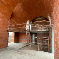 The interior of a house under construction, featuring two magnificent brick vaults. This traditional technique creates a space with incredible volume and a warm, earthy feel.