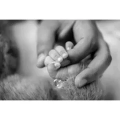 The same powerful image of a baby's hand gripping a parent's finger, rendered in timeless black and white. This style emphasizes the emotion and connection in the gesture.