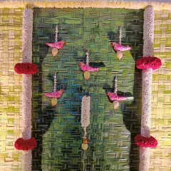 We love adding unique details to our decor. This close-up shows small, bird-shaped floral hangings made from pink flowers, adding a charming and artistic touch to a traditional pooja backdrop.