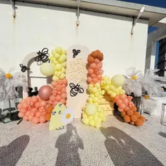 A look at our "Sweet as Can Bee" theme in action on a sunny rooftop. This setup features a vibrant balloon garland in shades of yellow and peach, oversized daisies, and adorable bee accents for a cheerful and playful baby shower celebration.