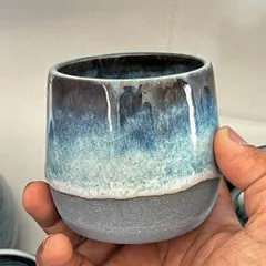 A close-up of a teacup, showing the rich, layered glaze that drips down the side.