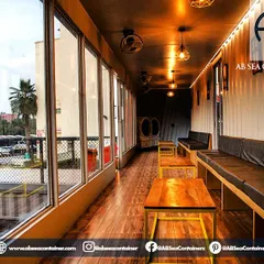 The interior of 'Cafe Infinity' uses warm, earthy tones and industrial-chic lighting to create an inviting lounge atmosphere. The corrugated container walls are integrated into the design, adding texture and character.