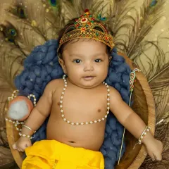 A beautiful portrait of a baby boy dressed as Bal Gopal for Janmashtami, complete with a crown and peacock feathers.