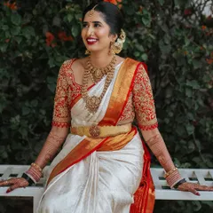 A full view of Chaitra's muhurtham outfit. The rich embroidery on the blouse sleeves balances the traditional temple jewelry and the classic elegance of the white silk saree.