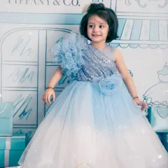 A glamorous toddler photoshoot with a "Tiffany & Co." theme. She looks like a little star in her sequined blue gown against the illustrated storefront backdrop.